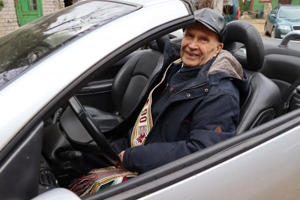 Garbaus amžiaus senolis laisvalaikiu sėda prie kabrioleto vairo